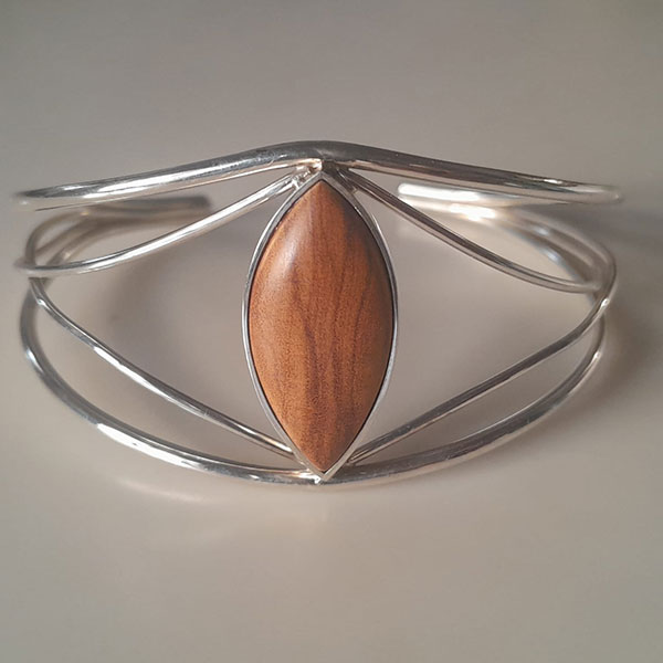 Brazalete abierto de plata reciclada y madera de olivo, diseño minimalista con centro ovalado en elegante acabado artesanal.
