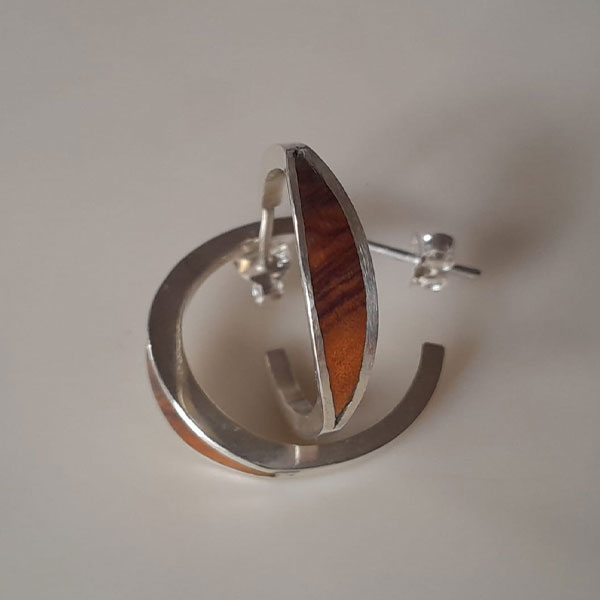 Pendientes de aro en plata reciclada y madera de olivo, fotografiados sobre un fondo claro, destacan su diseño artesanal.